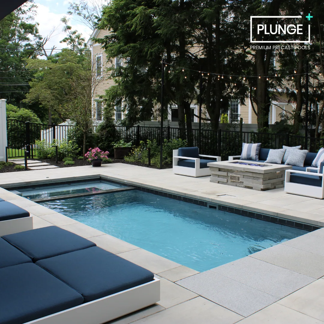 A backyard patio with a small rectangular pool, outdoor seating with navy cushions, string lights, and a garden with trees and plants.
