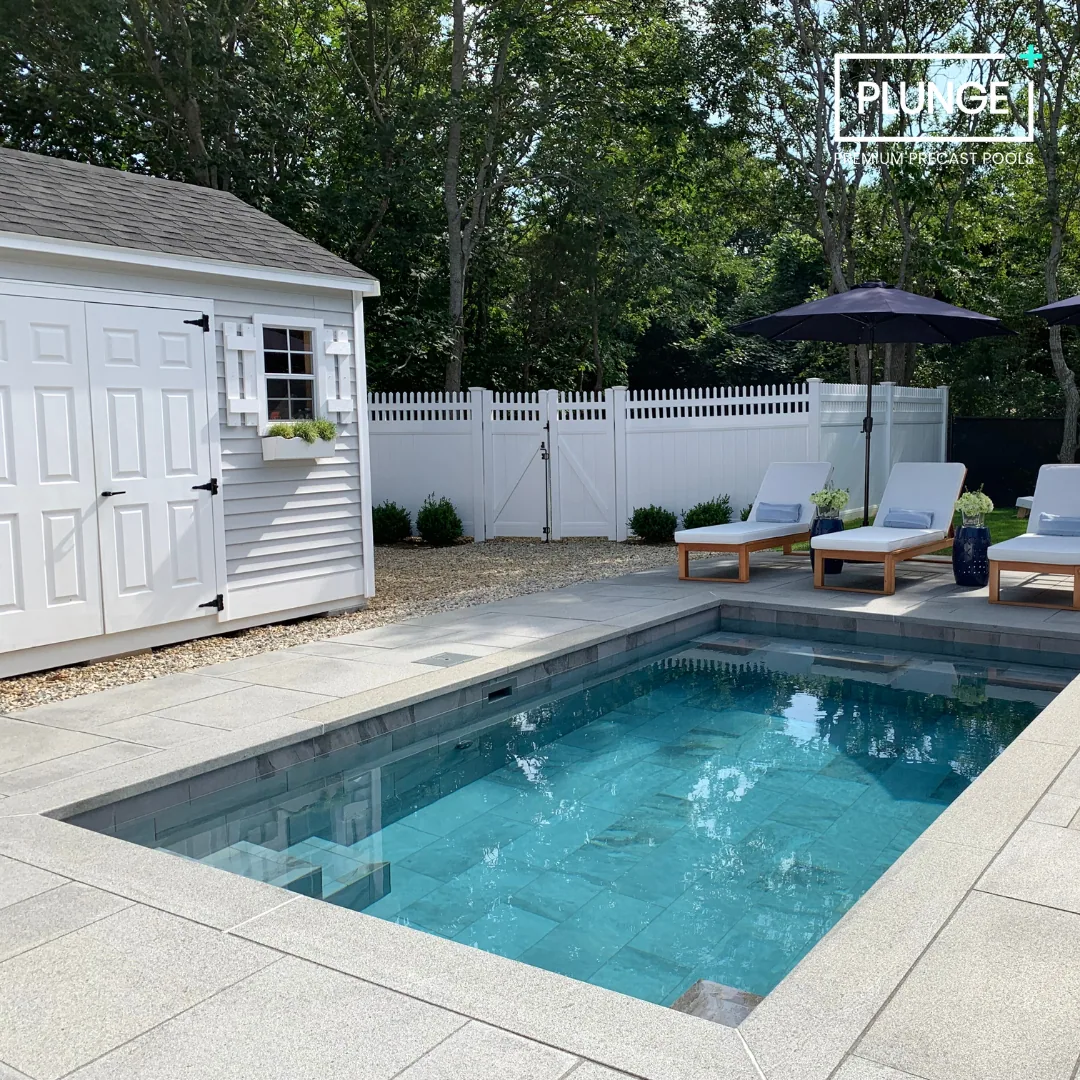 Backyard with a small in-ground pool, white shed, white fence, and lounge chairs with umbrellas