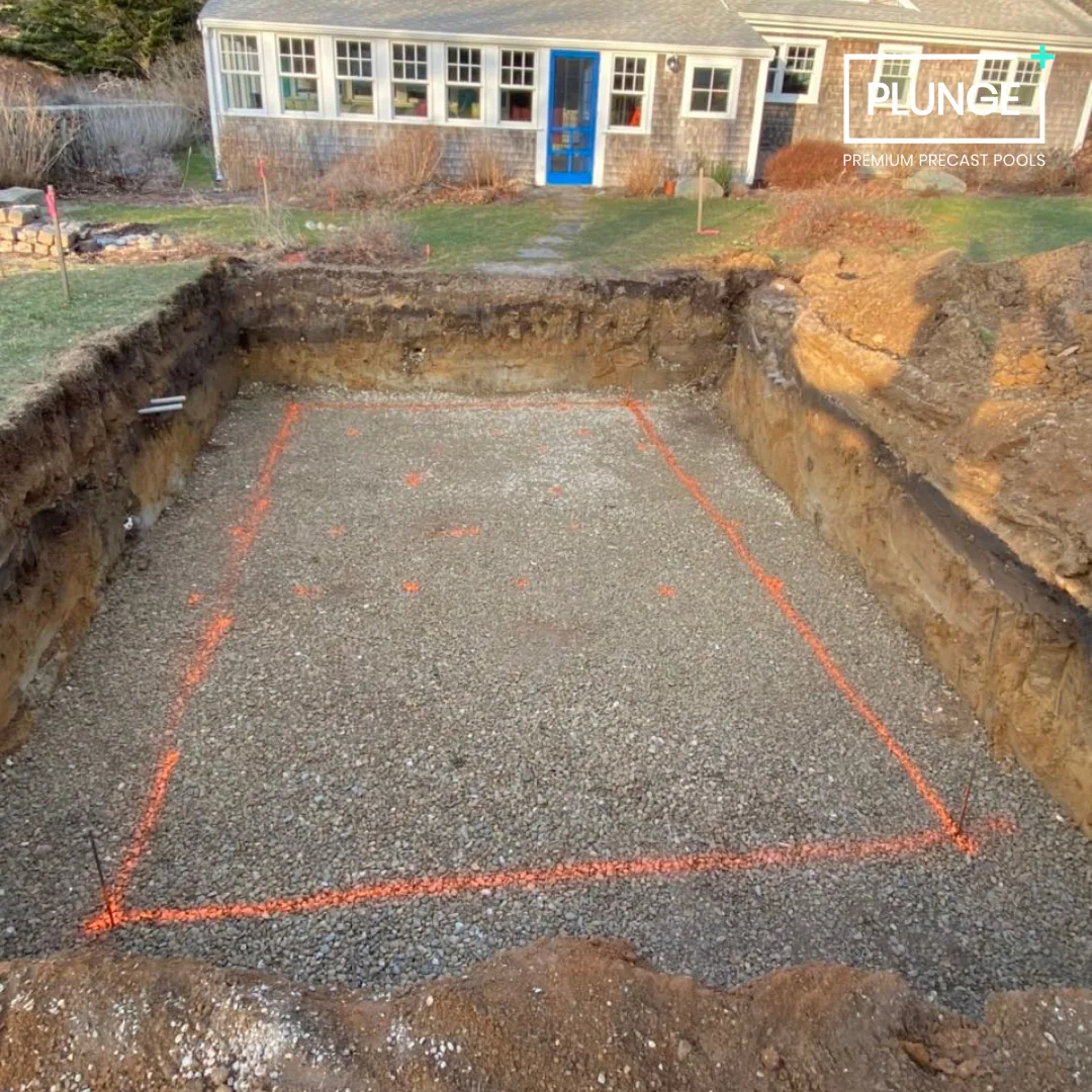 A backyard with a freshly excavated area outlined with orange spray paint, likely for a pool installation, with a house in the background.